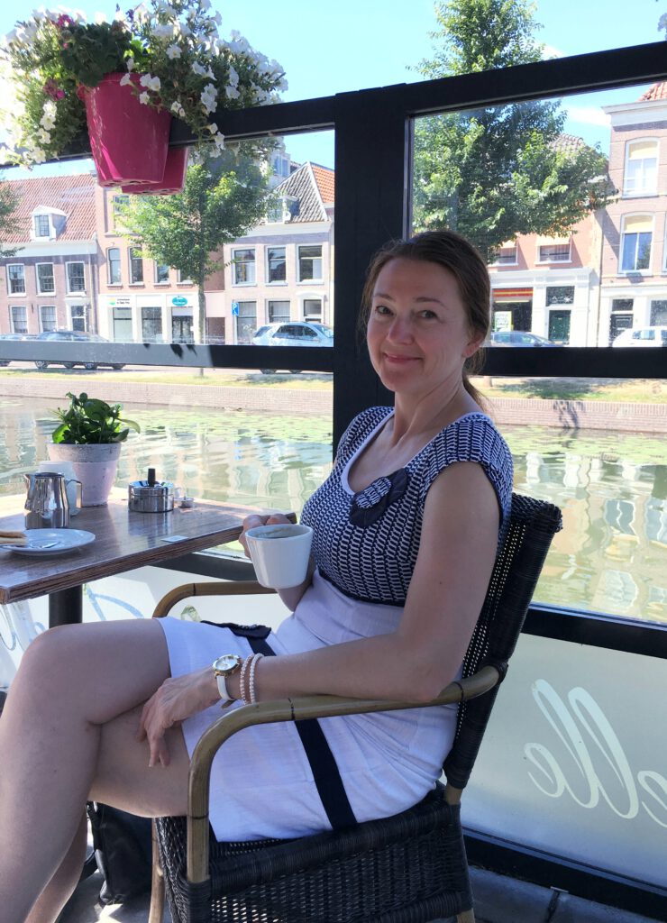 Woman is traveling through Holland, visiting picturesque town of Weesp, having cup of coffee
